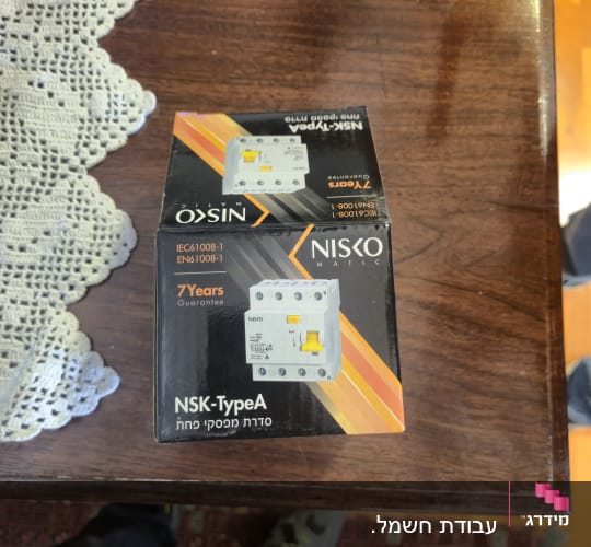 אריזת מפסק חשמלי של חברת Nisko על שולחן עץ